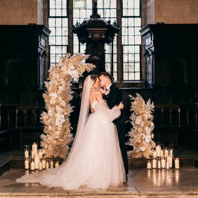 A couple stood in front of a broken flower arch getting married. 