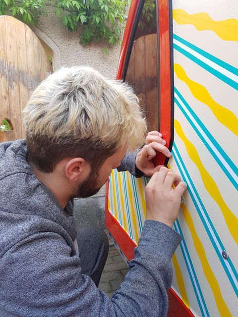 Tapeartist beklebt einen roten Caravan