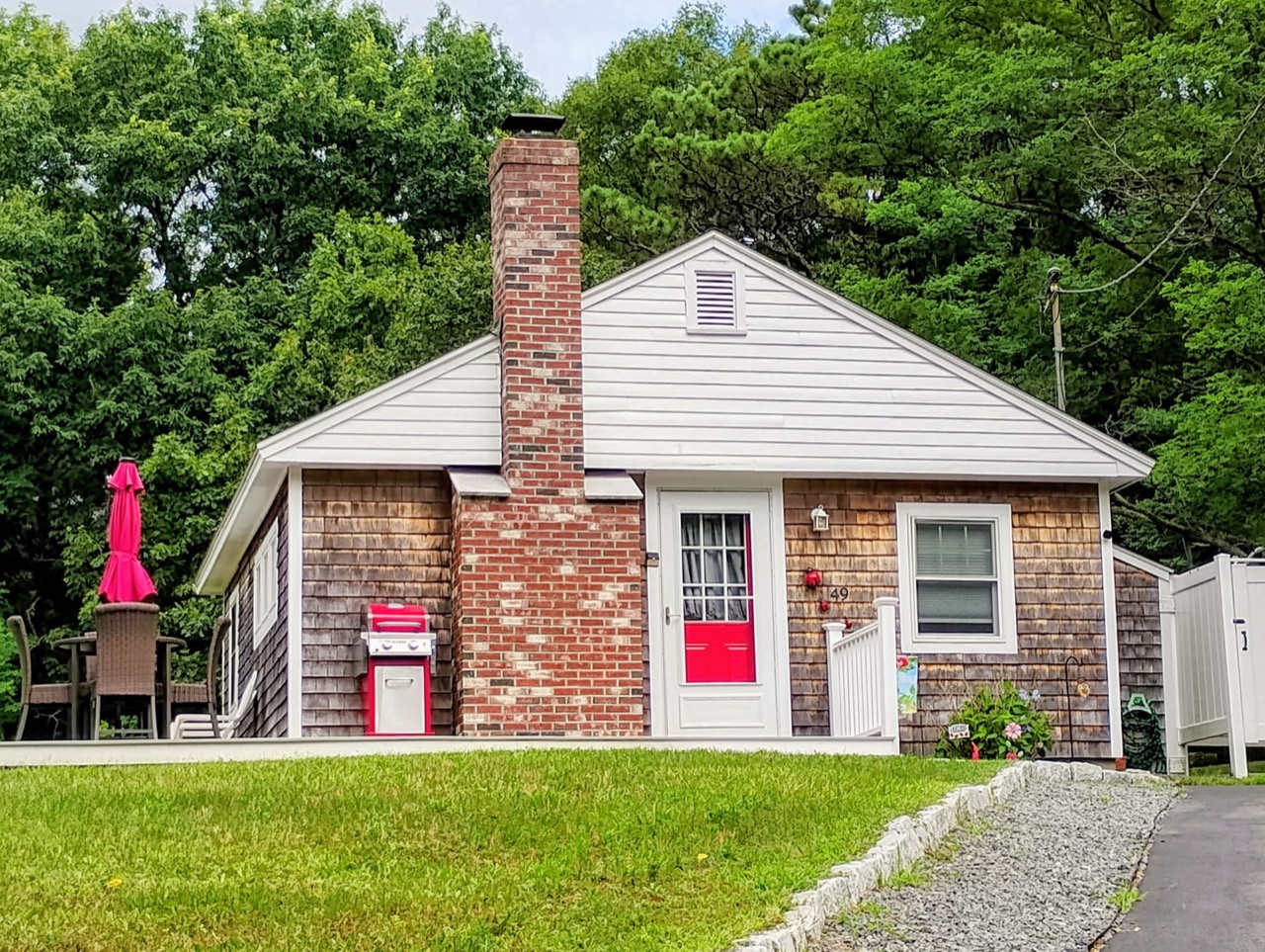 Ladybug Cottage front entrance with white railing, red door, and lawn