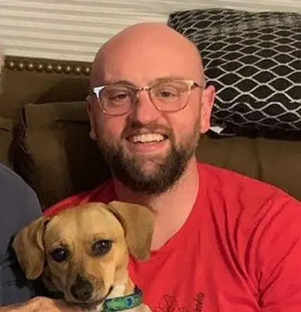 Alex Wilson sitting on a couch with a pet dog