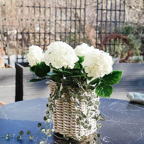 Terassin sisustus tekokasveilla –  tekokasvi hortensia-asetelma pöydällä