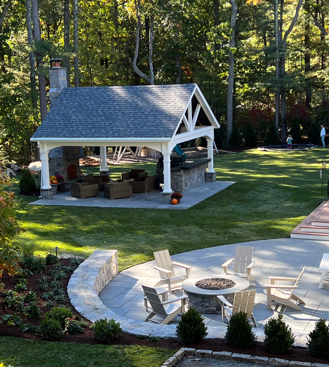 a backyard with a fire pit and a gazebo surrounded by forest