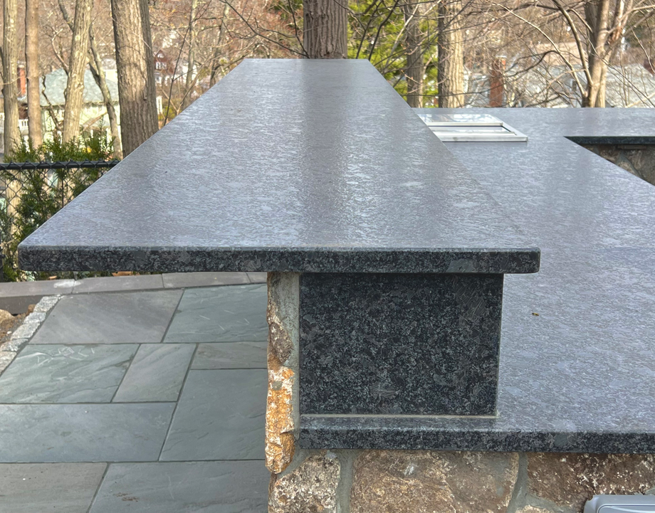 a black granite countertop on a patio in the middle of a wooded area