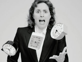 A woman in a suit looks panicked, juggling three clocks in mid-air against a plain background. The image is in
