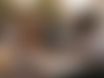 Una mujer con un kimono estampado y un hombre con una camisa estampada están sentados en una cafetería al aire libre y tienen una conversación animada. La mujer tiene el pelo rizado y lleva un collar y unos pendientes, mientras que el hombre tiene el pelo corto y lleva un reloj. Están sentados a una mesa redonda de madera con dos tazas de café, un plato de comida y un cuaderno. La mujer está gesticulando con las manos mientras habla, y el hombre le sonríe. Al fondo, otras personas disfrutan de sus bebidas y conversaciones. El café se llama "Le Café Linguistique".