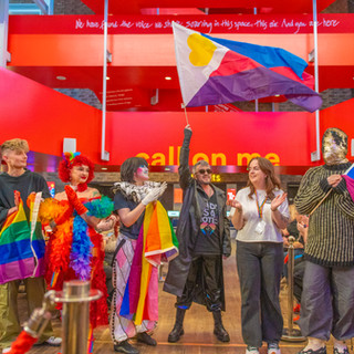 Group of queer spotlight performers celebrate and wave pan-sexual flag.