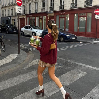 garota vestindo minissaia plissada xadrez, rabo de cavalo, suéter vinho, salto alto vinho, meia branca andando na rua