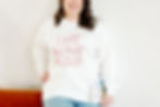 Smiling person in a white sweatshirt with "I JUST FEEL A LOT OF STUFF" in red text, holding a book titled "The Happy Empath's Workbook."