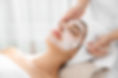 Cosmetologist applying mask on client's face in spa salon