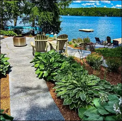 Luxury waterfront cottage landscape with stone pathway, garden beds, and lakeside seating