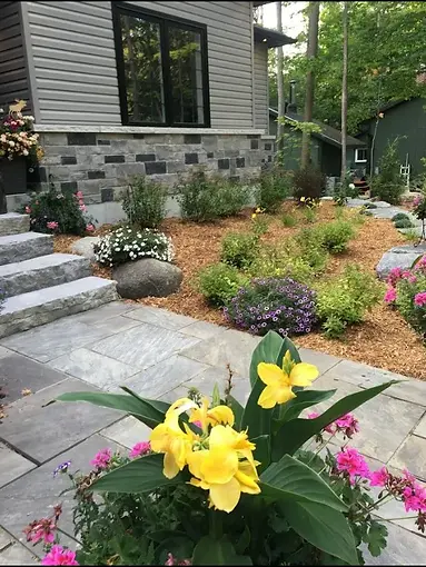 Luxury cottage softscape landscaping with stone patio, flowers, and custom garden beds