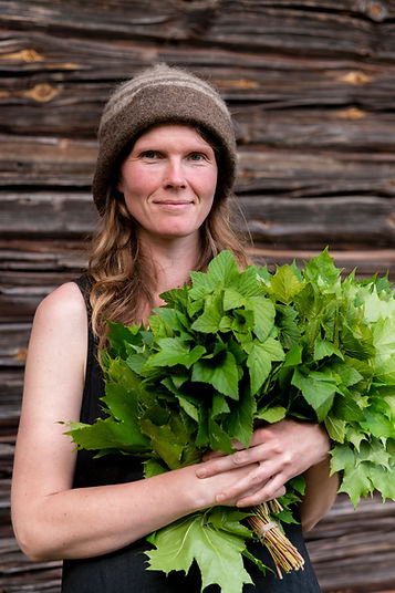 Perinnesaunottaja Sonja Linnala vasta sylissä saunan edustalla