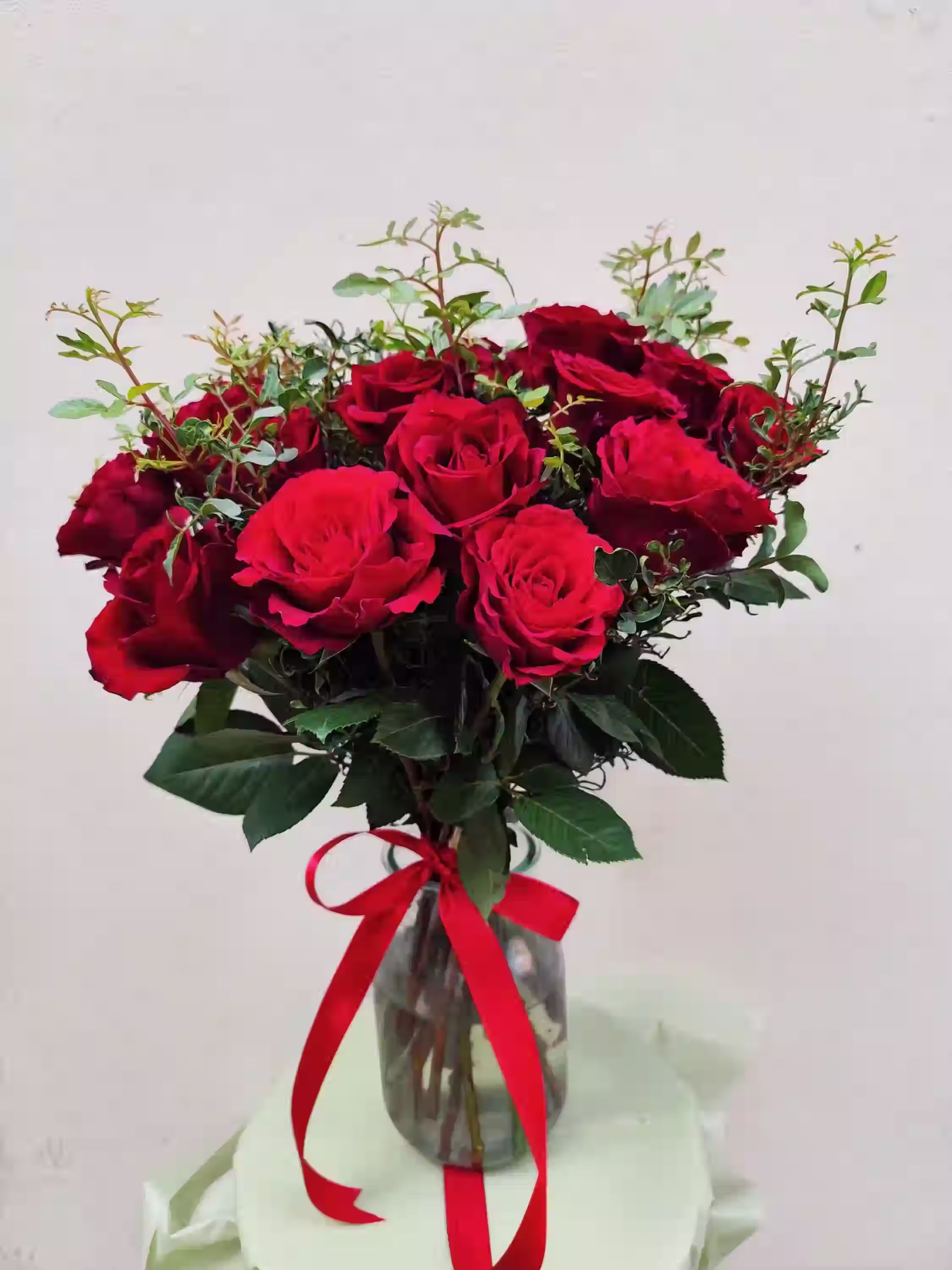 Elegant Roses Pistachio bouquet featuring 16 deep red roses with velvety petals and pistachio greenery