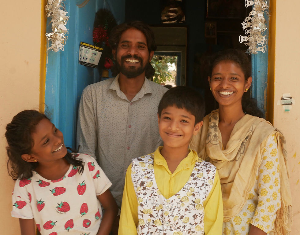 Family looking at camera and smiling next to a blue door and orange wall.