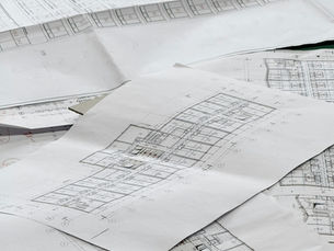 Planos arquitectónicos extendidos sobre una mesa, representando la planeación financiera de un desarrollo inmobiliario