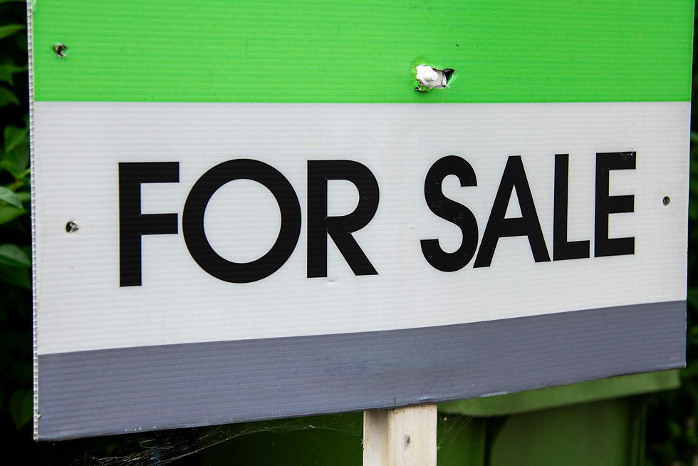 Letrero de 'se vende' frente a una casa, ilustrando la incertidumbre del mercado inmobiliario por el alza de tasas de interés en EE.UU.