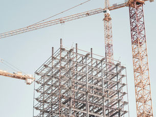Edificio en construcción con estructura de acero y grúa, ilustrando los sobrecostos e imprevistos de un desarrollo inmobiliario