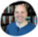 Smiling man in blue shirt, bookshelves background