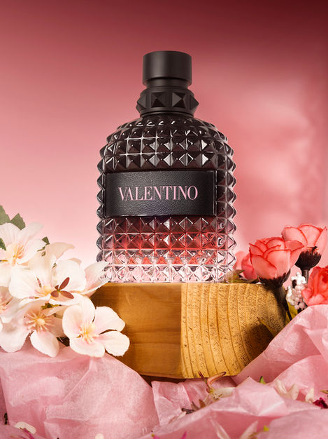 Fotografía publicitaria: producto de perfumería con atrezzo de flores y tonos rosados a juego con los colores del producto