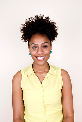 black woman with her hair up smiling in a yellow shirt supporting early breast cancer detection.