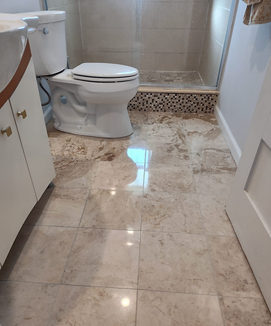 Clean beige bathroom tile floor, toilet, and shower