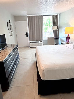 Hotel room with bed, television, dresser; window, and lamp. The Lisbon Extended.