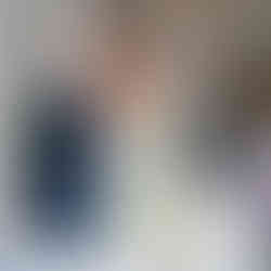 An artistic shot of the newly weds in the background and a blue tapered candle and matching florals in the foreground.