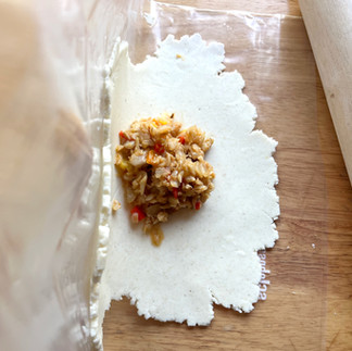 adding fish filling to empanadas