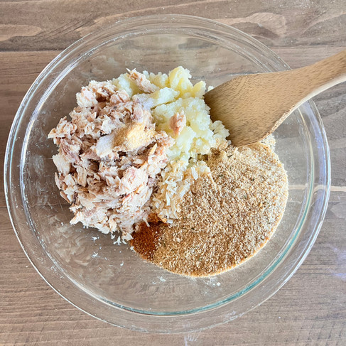 Mixing  mashed potatoes with bread crumbs, tuna, seasonings