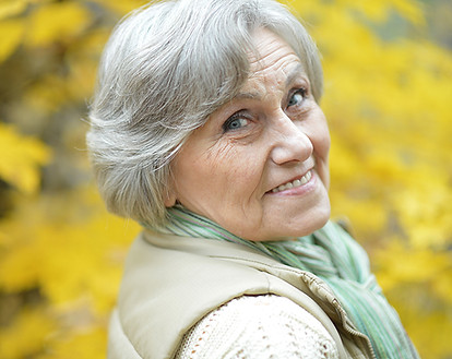An elderly woman with grey hair smiling because she is content with her financial plans