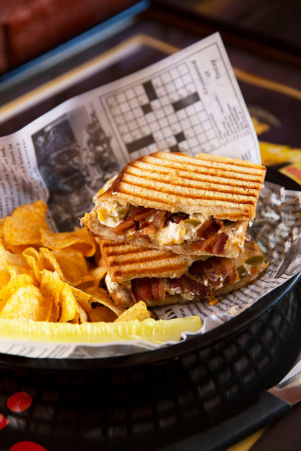 Cheesy sandwich with jalapenos and bacon cut in half with bar-b-que chips on a plate