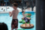 A young boy waits his turn while his brother challenges himself to cross the lap pool at River Rapids on floating foot pads and a hanging net