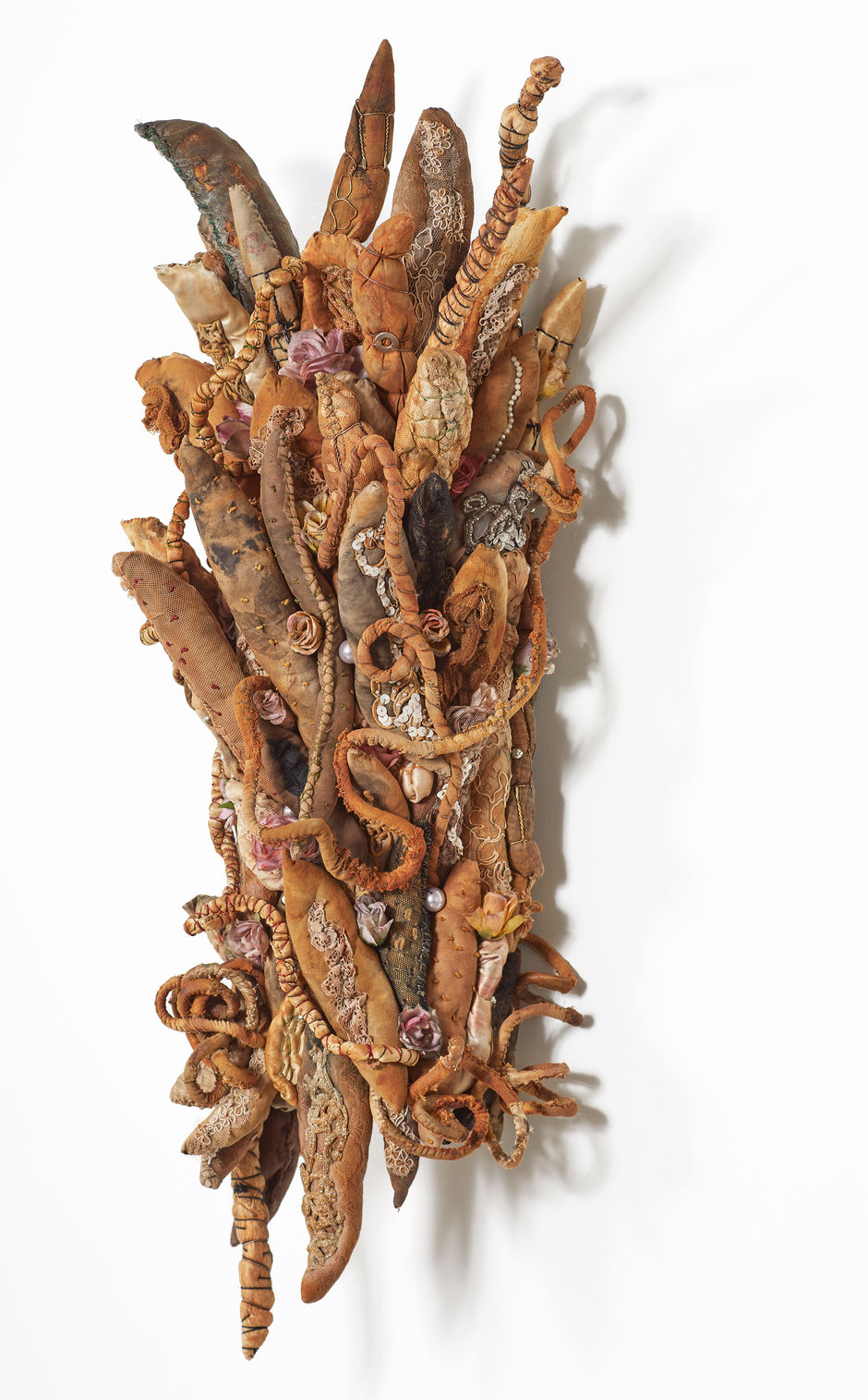 Vertical rust dyed cluster sculpture. Poufs are assembled on hardware cloth form, embellished with silk roses.