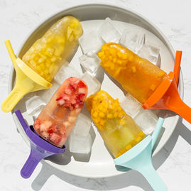 Fruit tea popsicles with chunks of fruit laid on a plate with ice