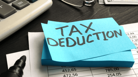 Blue sticky note with "Tax Deduction" written on it placed on financial documents beside calculator, representing Australian small business tax planning, sydney accountant, tax return, accounting services ,,Australia  small business, accounting  business, accountant Sydney,  registered tax agent, professional accounting firm, certified accountant, bookkeeping and accounting, BAS and GST services