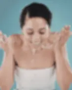 Young woman washing her face with rice water in a bathroom during a natural skincare ritual