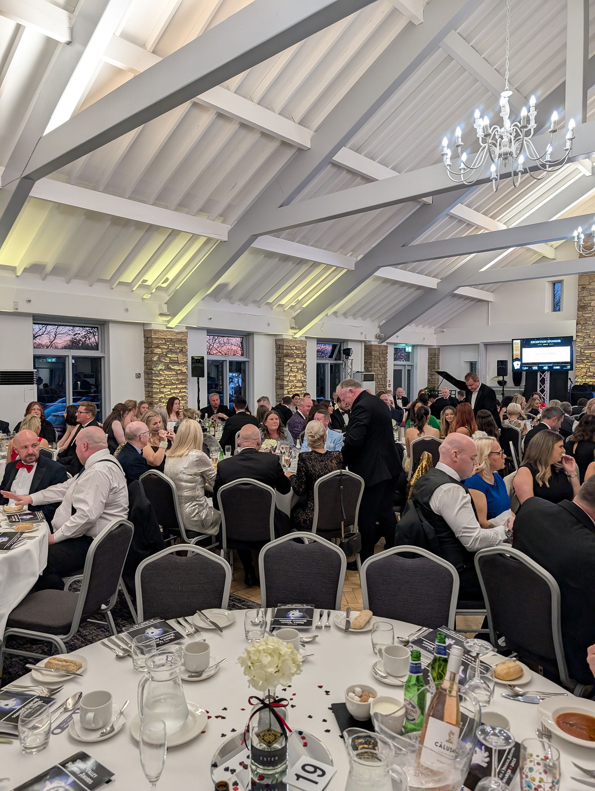 a large room of tables and chairs with guests dressed in blacktie for a dinner
