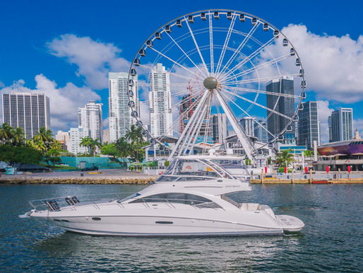 52ft Sea Ray Sedan Bridge yacht cruising in front of Bayside Marketplace and the Ferris wheel — a stunning view for a half day yacht rental in Miami.