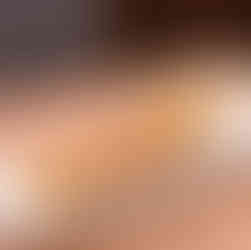 Four crispy arancini balls on a white plate with a charred lemon half and dipping sauce. Set on a wooden table, warm outdoor ambiance.