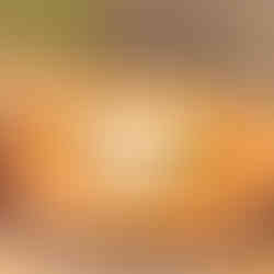 Pizza topped with burrata and basil on a wooden table. The crust is golden, and the setting is a cozy, rustic dining area.