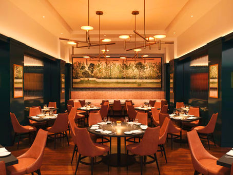 Elegant restaurant interior with empty brown chairs and round tables set for dining. Warm lighting, decorative wall art, and cozy ambiance.