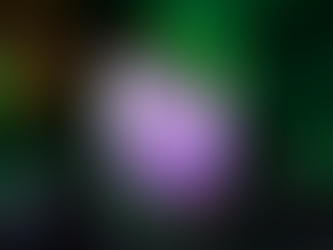 Purple cocktail in a glass with ice, garnished with mint. Halloween-themed setting with a jack-o'-lantern, creating a spooky mood.