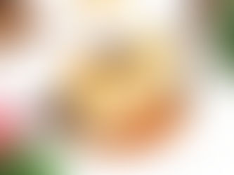 A cake resembling a wrapped candy with chocolate curls sits on a golden base. Surrounded by pinecones and red berries, creating a festive feel.