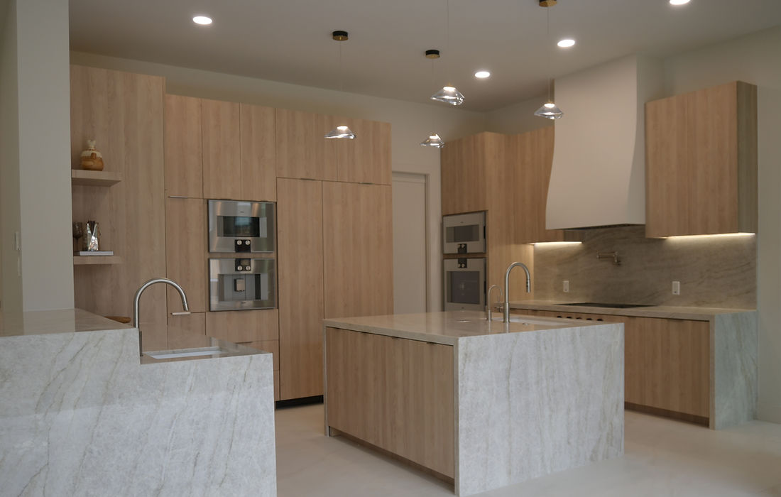 Organic modern kitchen featuring white oak european style cabinetry, luxury appliances, and Taj Mahal quartzite countertops.