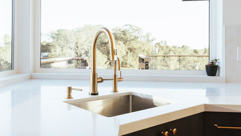a kitchen sink with a gold faucet