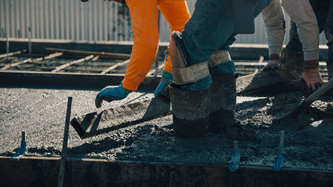 a person wearing a pair of flex knee pads pouring concrete