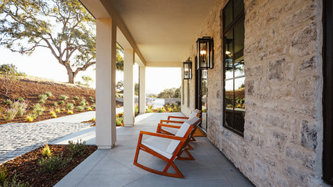 a porch with rocking chairs and lanterns on the wall