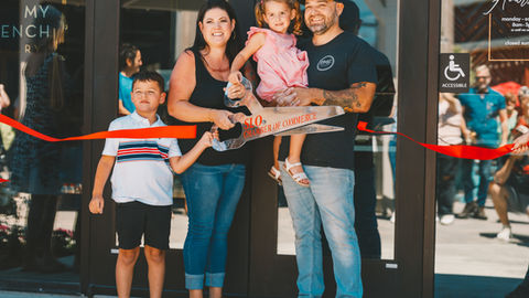 a family cutting a red ribbon with a pair of scissors that say slo chamber of commerce