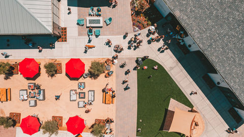 a large group of people are gathered in a courtyard with umbrellas and tables