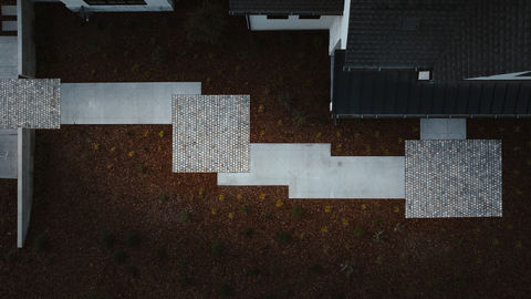 an aerial view of a brick walkway leading to a house